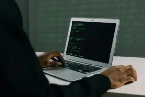 A focused adult working on a laptop demonstrates modern cybersecurity and coding skills indoors.